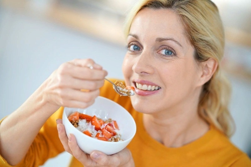 Женщина подносит ложку с салатом ко рту